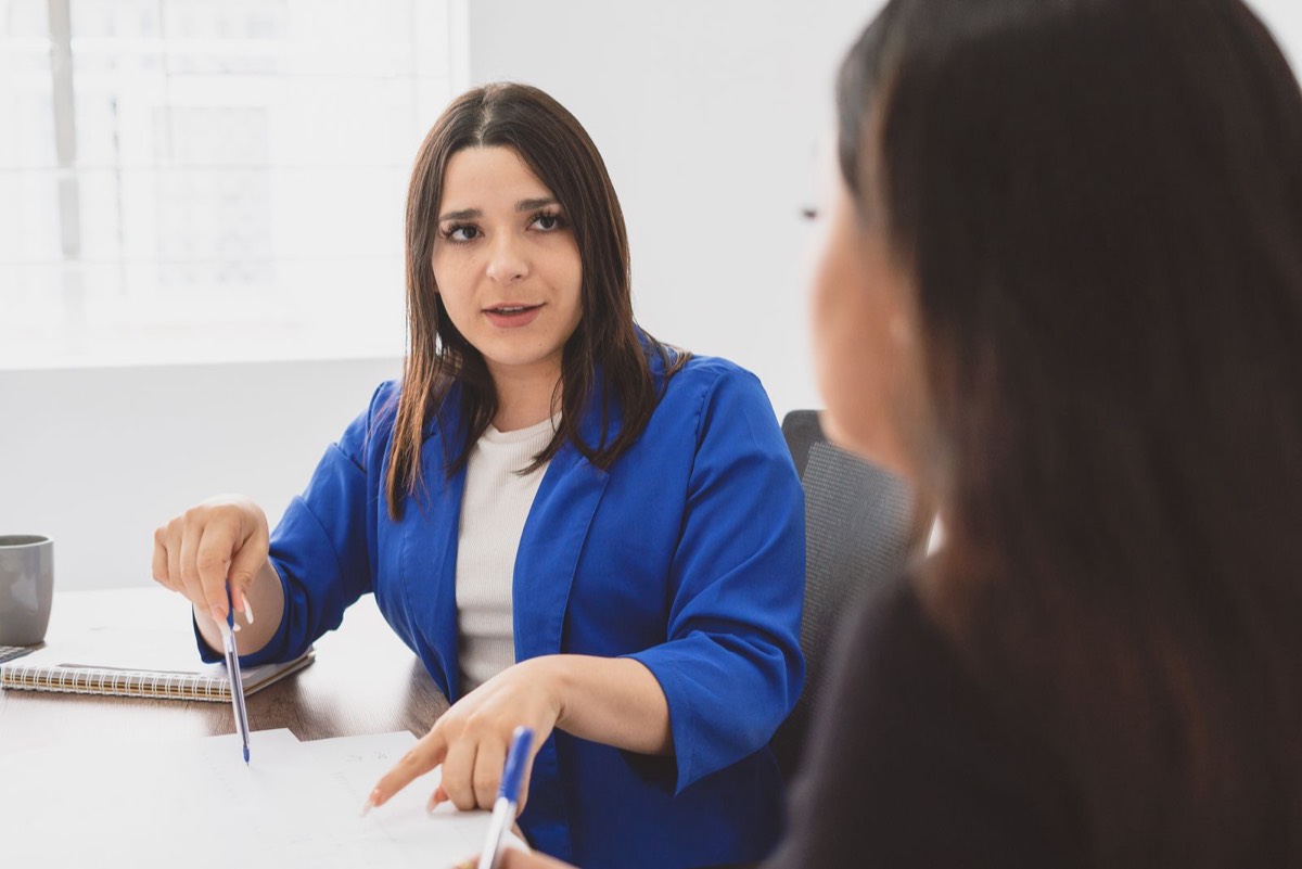 Dos profesionales conversan sobre un documento en una reunión de trabajo